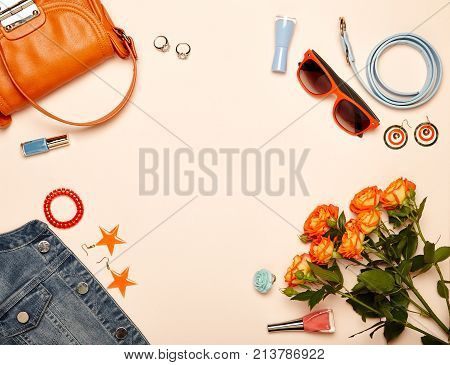 Fashionable Women's Cosmetics and Accessories. Falt Lay. Nail Polish and blush. Jewelry and Rings. A bouquet of flowers. Orange roses. Handbag and Denim Jacket