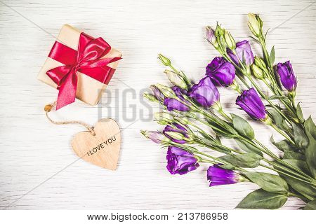 Purple flowers and box with a gift on a white background. Celebratory concept.