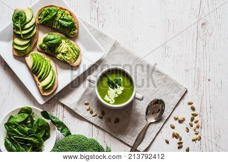 Vegetarian healthy food. Soup and vegan sandwiches. Different sandwiches with avocado. Brunch on white wooden background.