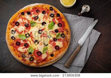 Pizza margarita with tomatoes mazarella and slices of olives on a dark concrete or stone background. Traditional Italian cuisine. Selective focus. Top view.