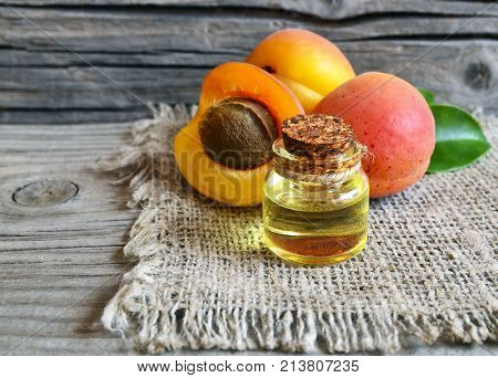 Apricot oil from apricot kernels in a glass jar and fresh ripe apricots on old wooden table.Essential apricot kernel oil for spa,beauty treatment,aromatherapy and bodycare. Selective focus.