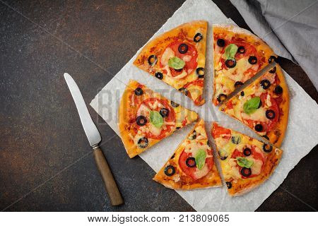 Pizza margarita with tomatoes mazarella and slices of olives on a dark concrete or stone background. Traditional Italian cuisine. Selective focus. Top view.