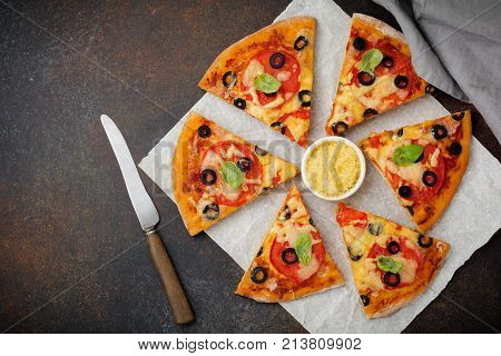 Pizza margarita with tomatoes mazarella and slices of olives on a dark concrete or stone background. Traditional Italian cuisine. Selective focus. Top view.