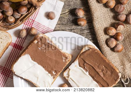 sliced bread with nutella cream on wooden table.
hazelnuts on table