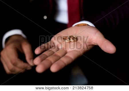 The groom holds the rings on his hand. Morning of the groom.