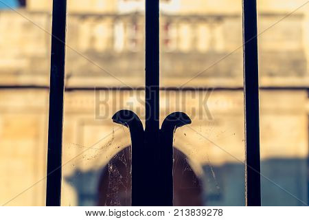 blurred stone building behind a black wrought iron fence in France