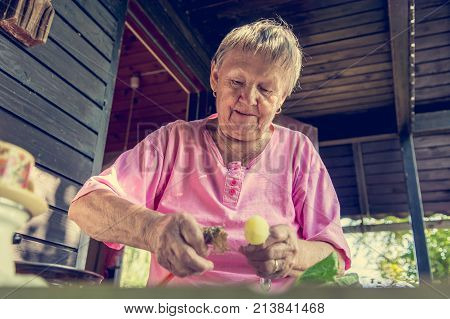 Senior woman pealing potatoes. Granny cooking delicous food.
