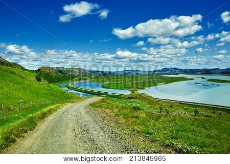 Travel to Iceland. road and river in a bright sunny mountain landscape. Vatna volcano covered with snow and ice on tne background.