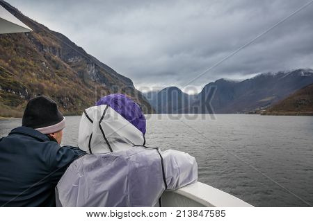 Middle aged couple admiring stunning scenery during Norway in a nutshell sightseeing cruise through the Aurlandsfjord and  narrow Naeroyfjord