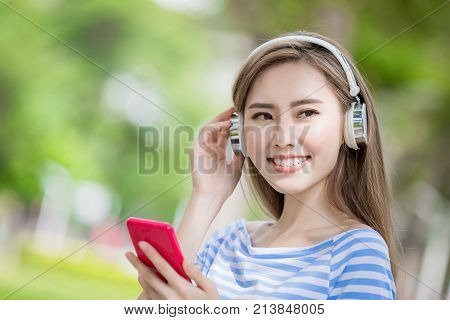 woman smile happily and use phone listen music in the park