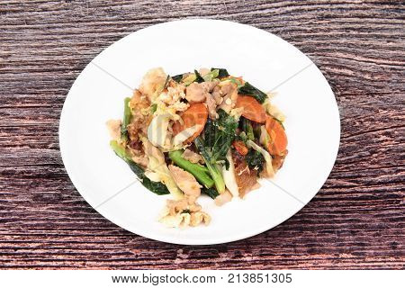 Fried big noodle with marinated chicken in soy sauce and vegetable call Sen Yai Pad Cee Oue in Thai.