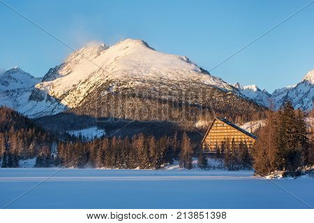 Winter view of the Strbske pleso village with hotel coniferous forest and snowy peaks. The village is a favorite ski tourist and health resort in the slovakian part of High Tatras mountains.