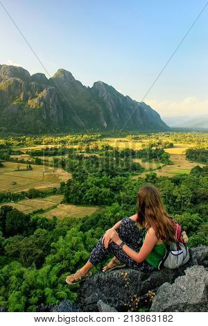 Young woman enjoying the view of farm fields in Vang Vieng Laos. Vang Vieng is a popular destination for adventure tourism in a limestone karst landscape.