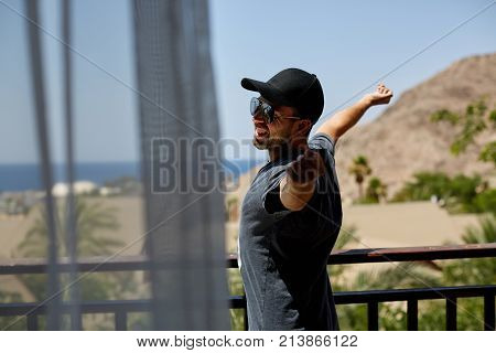 Summertime handsome man walking on the streets he has a take away mug of coffee at hand