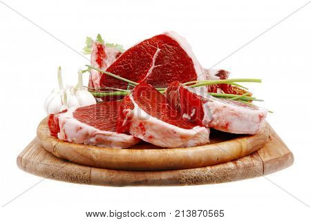 fresh meat : raw uncooked fat lamb pork rib and fillet with green stuff and red chili pepper on wooden plate isolated over white background