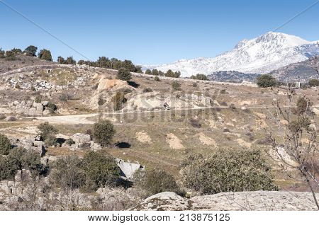 Mountainbiker in Guadarrama Mountains, Colmenar Viejo, Madrid, Spain, on February 8 2015. In the background can be seen The Maliciosa Peak