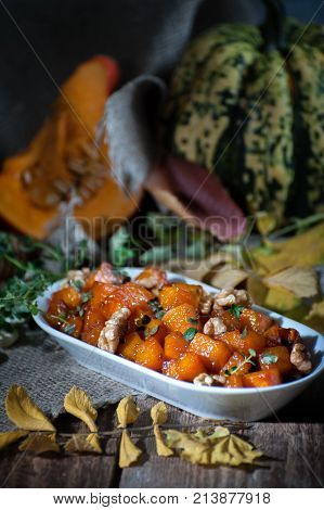 A Tender Baked Pumpkin With Honey, Nuts And Thyme Leaves. Shooting In Dark Tones With A Light Brush.
