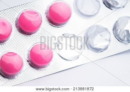 Top view of used blister pack of magenta tablets medical pills in silver foil pack on white background.