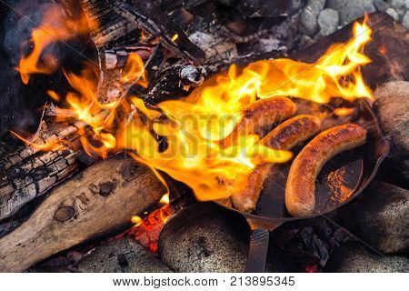 Cooking Sausages In Cast Iron Skillet On Campfire While Camping. Good And Positive Campfire Food.