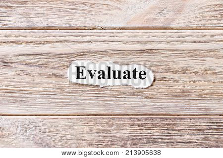 Evaluate of the word on paper. concept. Words of Evaluate on a wooden background.