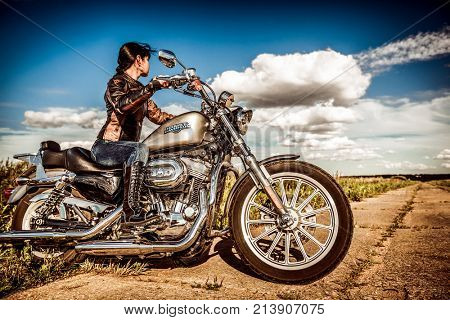 RUSSIA-JULY 7, 2013: Biker girl and bike Harley Sportster. Harley Davidson sustains a large brand community which keeps active through clubs, events, and a museum. Filter applied in post-production.