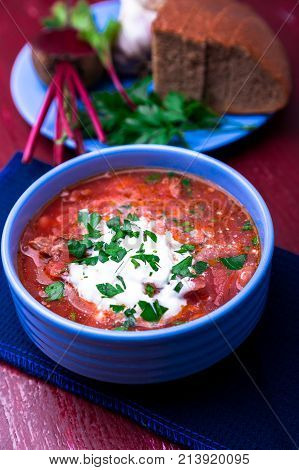 Ukrainian Traditional Borsch. Russian Vegetarian Red Soup  In Blue Bowl On Red Wooden Background.  B
