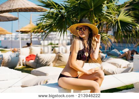 Rich lifestyle woman relaxing enjoying luxury beach hotel,palms and umbrella around,expensive resort,summer vacations