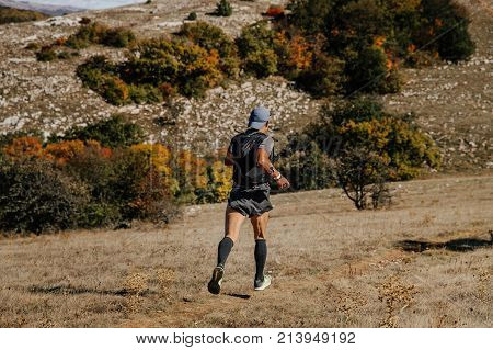back male athlete runner running mountain trail