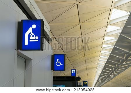 Illuminated signboard for deaper changing rooms and disabled toilet in international airport with copy space for text. Baby changing room sign lightbox in airport.