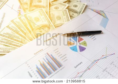 Business concept ball pen Financial report and U.S. dollar bills on the table