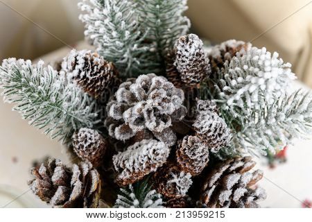 Winter holidays background of pine cones powdered with artificial snow and white downy shawl. Merry Christmas brown backdrop.
