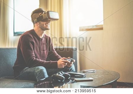 Young gamer playing video games virtual reality glasses in his apartment - Happy man having fun with new trends technology - Gaming concept - Focus on goggles headset - Contrast filter