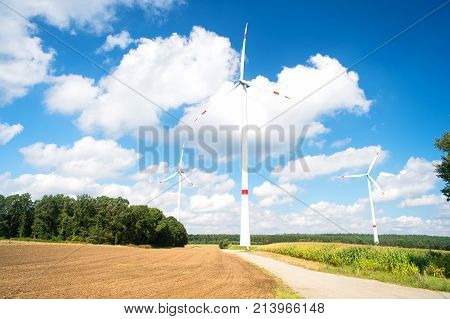 Wind farm in Lower Saxony Germany. Turbines on field on cloudy blue sky. Alternative energy source. Global warming climate change. Eco power green technology concept.
