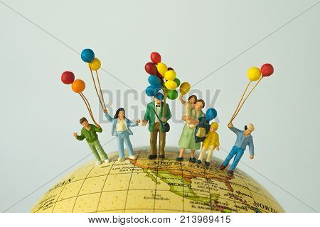 miniature people figure happy family holding balloons standing on united states of america map on globe as world climate change or happy american family concept.
