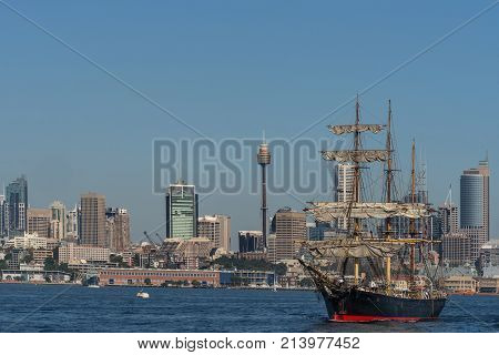 Sydney Australia - March 26 2017: Sailing tall black and red ship with downtown skyline in background on blue water and under clear skies.