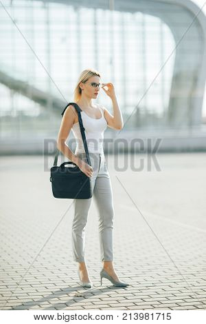 The image of a business woman standing on the street at sunset