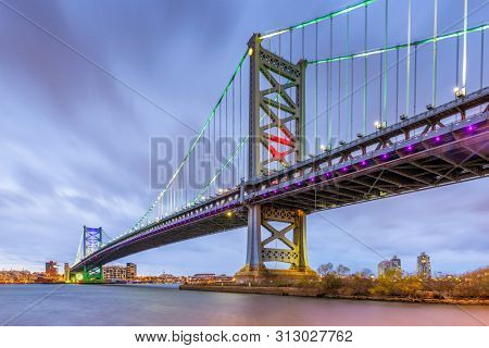 Philadelphia, Pennsylvania, USA skyline on the Delaware river with Ben Franklin Bridge at night.