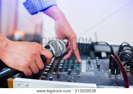 Microphone In Hand And Adjust An Audio Mixer Controller In The Control Room, Sound Mixer Control For