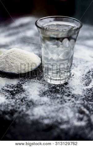 Rice Water In A Glass Bowl Along With Rice Grains & Its Powder Also On Wooden Surface & Some Rice Po