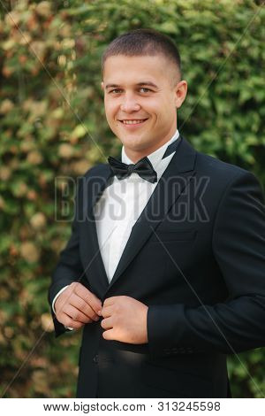 Young Man Walking In The Park. Handsome Groom In Black Suit