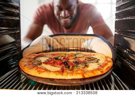View Looking Out From Inside Oven As Man Cooks Fresh Pizza