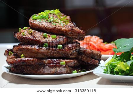 Delicious juicy grilled pork chop steak with fresh homegrown vegetable salad, tomatoes, sweet and sour carrot, radish. Hot Meat Dishes. 