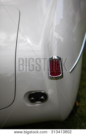 Close Up Vertical Image Of The Red Tail Light And Exhaust Pipes Of A White Classical Vintage Car.