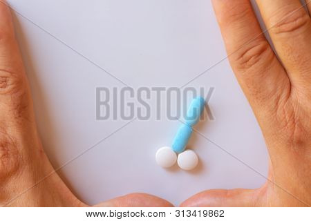 Hands Of A Man Next To Pills That Symbolize A Penis With An Erection. Male Metaphor. Medicine Relate