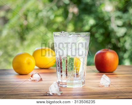 Fruit Composition On Brown Desk, Close Up View. Yellow Lemons, Red Apple, Three Ice Cubes And Glass 