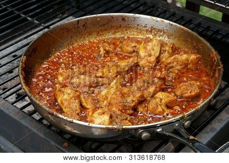 Stirring And Cooking Tava Chicken Outdoors In A Pan On Coals.