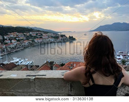 A Young Woman Admiring The View From A Top The Bell Tower In The Town Of Korcula During Sundown Of T