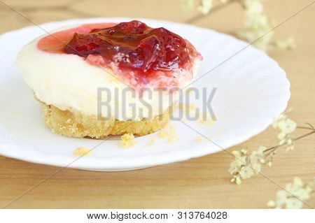 Close Up One Piece Of Strawberry Cheesecake With Red Strawberry Sauce , Side View On Wooden Table Ba