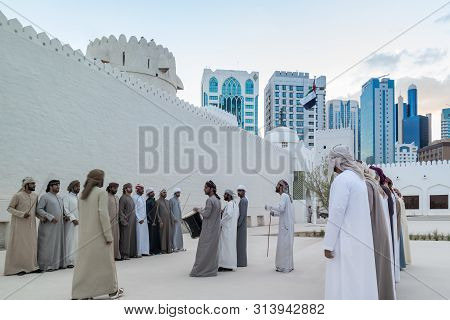 Emirati Middle Eastern Men Performing A Traditional Dance (the Yowla) Next To Al Hsin Building, The 