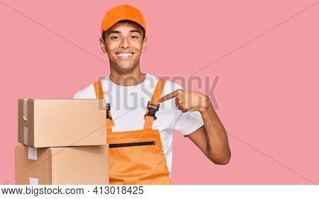 Young handsome african american man holding delivery package pointing finger to one self smiling happy and proud 